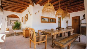 A rustic dining area with a wooden table, benches, and woven light fixtures.