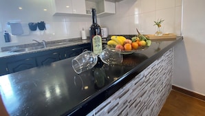 Una cocina moderna con encimera negra, armarios blancos y una campana extractora de acero inoxidable.