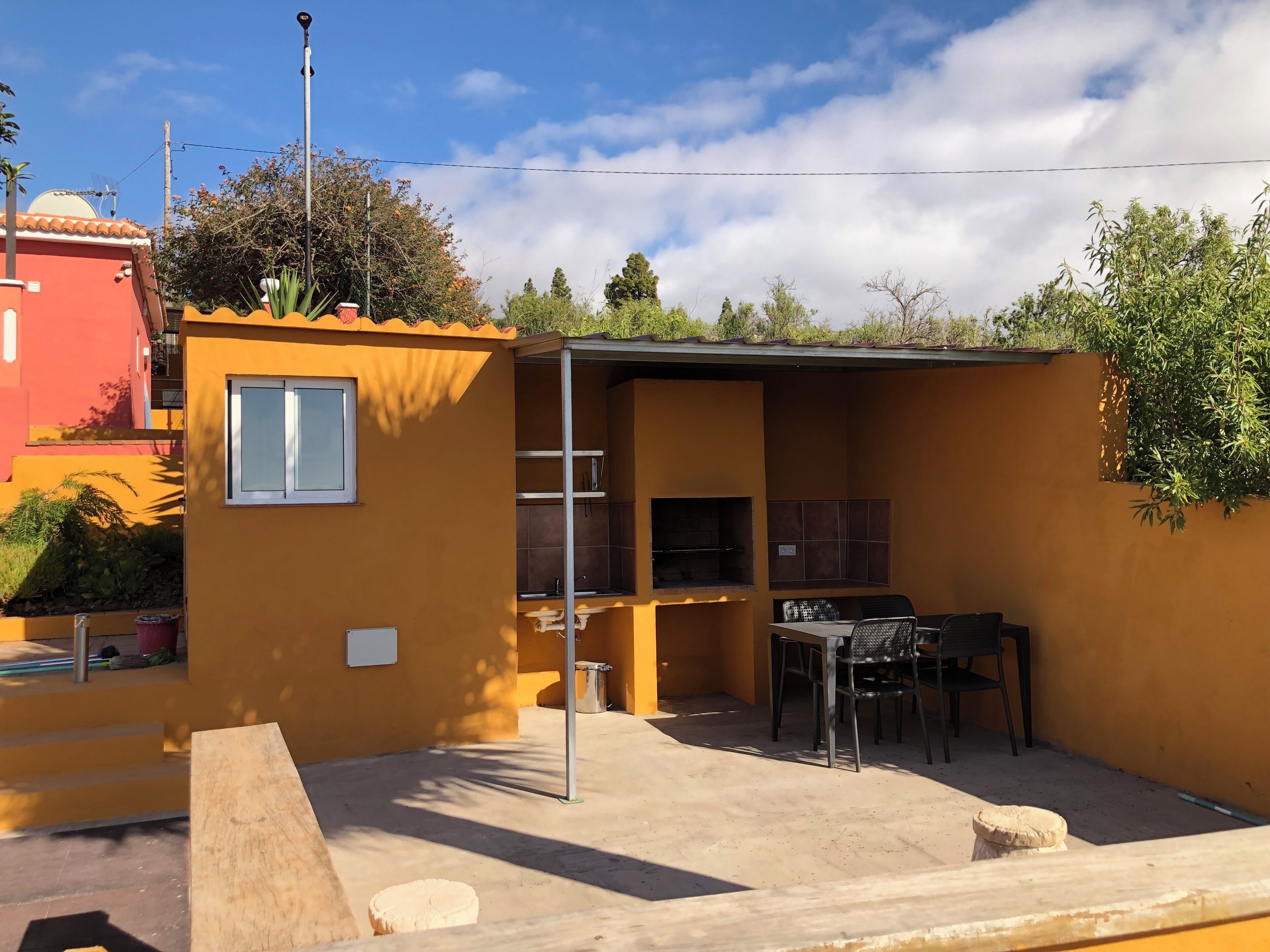 Un petit espace extérieur aménagé en patio, avec un barbecue, une table et des chaises, et une fenêtre.