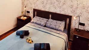Un dormitorio con una cama grande, dos mesitas de noche, un aire acondicionado de pared y un papel tapiz estampado.