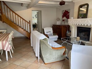 Uma sala de estar acolhedora com escada de madeira, área de jantar com toalhas de mesa listradas e lareira.