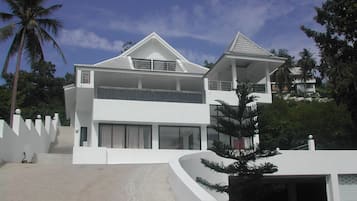 Een modern huis met twee verdiepingen, een balkon, grote ramen en een witte gevel.