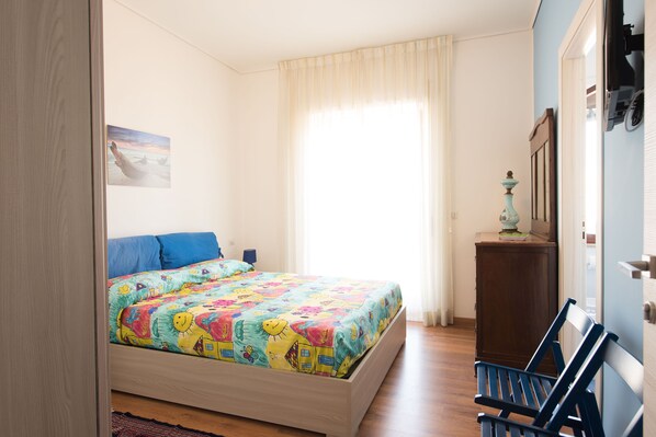 Un dormitorio con cama, una silla, un armario y un cuadro en la pared.