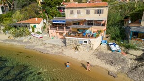 A coastal building with a balcony, a beach in the foreground, and a clear view of the sea. - APPARTAMENTO IL SOTTOMARINO - IL SOTTOMARINO (Portoferraio)
