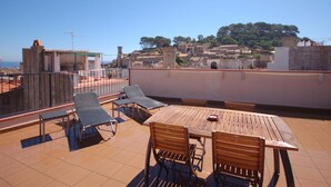 A rooftop terrace with a table and chairs, a view of a historic town, and a clear sky.