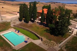 Una propiedad con piscina, un patio cubierto y vistas a colinas ondulantes.