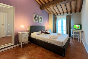 A bedroom with a bed, bedside tables, a television, and a mirror. - Borgo del Silenzio - Gelsomino two-bedroom apartment with private terrace (Provincia di Pisa)