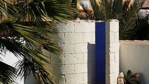A corner of a building with a white textured wall, a blue tiled section, and a small statue.