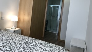 Ein Schlafzimmer mit einem Bett, einer Nachttischlampe, einer Holzvertäfelung und einer Duschkabine aus Glas.