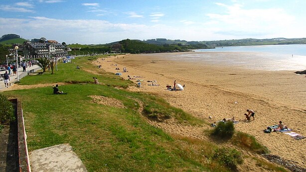 Une plage où des gens se prélassent au soleil et se promènent le long du rivage.