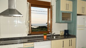 Une cuisine avec vue sur la mer, une cuisinière, un lave-vaisselle et des placards.