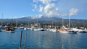 Un port de plaisance où sont amarrés de nombreux voiliers, avec en arrière-plan un paysage montagneux et un ciel dégagé.