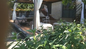 Un espace extérieur abrité, avec des tables et des chaises, un escalier et un mur en pierre.