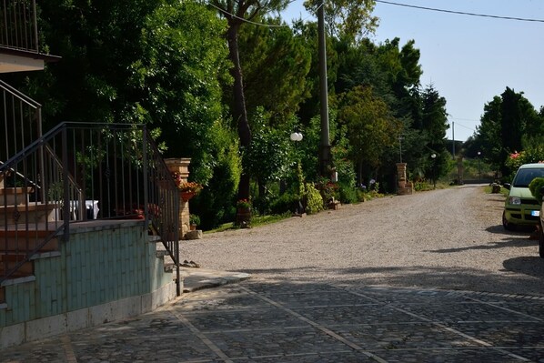 A cobblestone street with a green car parked on the right.