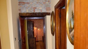 Un couloir avec un sol carrelé, des portes en bois et un mur en pierre.
