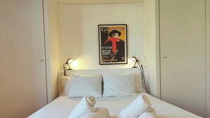 A neatly made bed with two rolled towels, a poster on the wall, and two bedside lamps. - Gorgeous views over La Rambla. Very bright! R.A. (Barcelona)