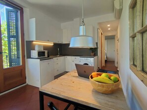 Une petite cuisine équipée d’un four à micro-ondes, d’un lave-linge et d’un ordinateur portable posé sur le plan de travail.