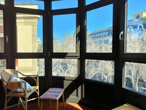 Une pièce dotée d’une grande fenêtre, de meubles en osier et d’un banc.