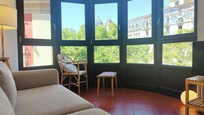 A room with a large bay window, a wicker chair, a small stool, and a sofa. - Gorgeous views over La Rambla. Very bright! R.A. (Barcelona)