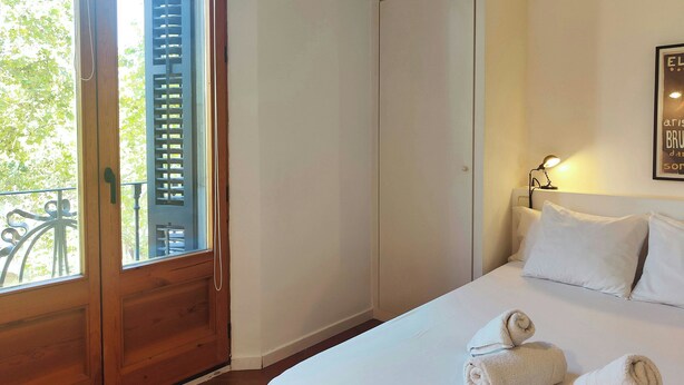 A bedroom with a bed, a door, a window, and a wall-mounted light. - Gorgeous views over La Rambla. Very bright! R.A. (Barcelona)