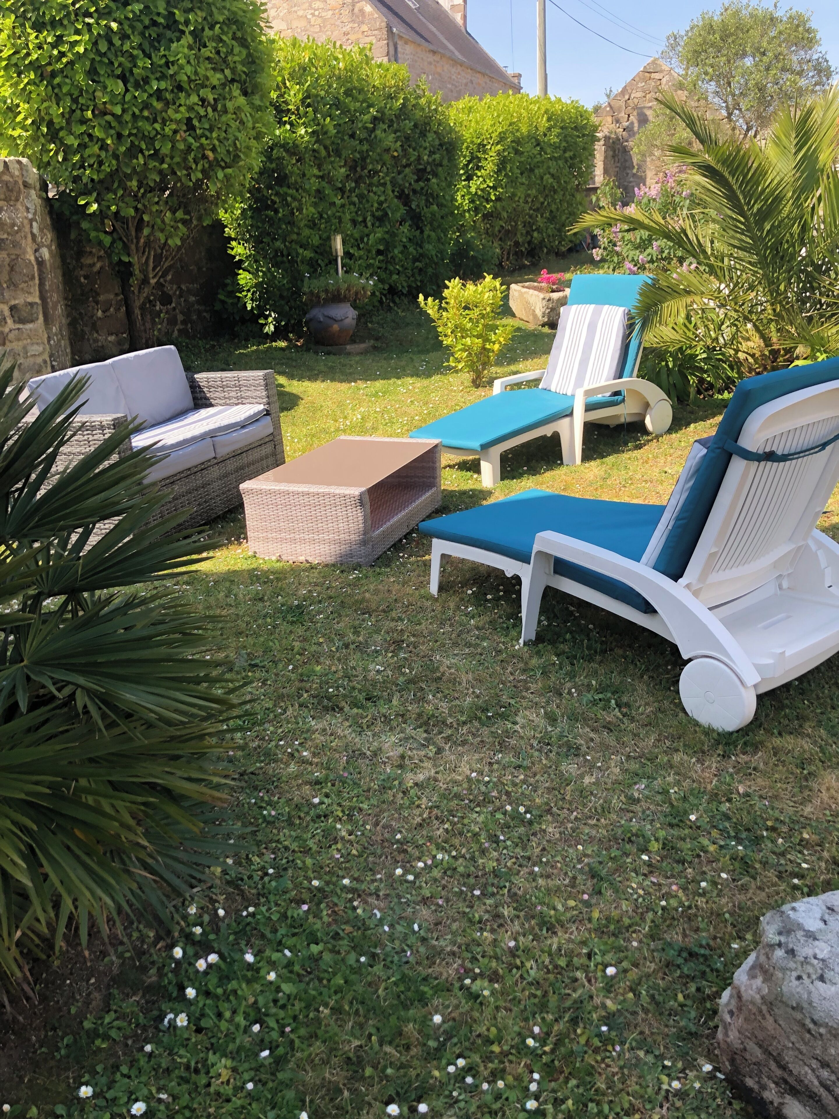 Ein Garten mit Gartenmöbeln, einer Steinmauer und einem kleinen Baum.