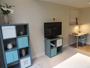 Cozy living space with a TV, desk, and shelving unit for storage.