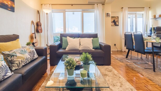Een woonkamer met een bank, een glazen salontafel en een eethoek met stoelen en een tafel.