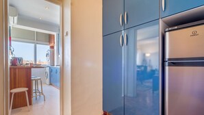 Een moderne keuken met een roestvrijstalen koelkast, houten vloeren en uitzicht op de stad door het raam.