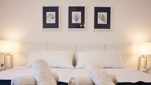 A hotel room with a large bed, two bedside lamps, and three framed artworks on the wall.