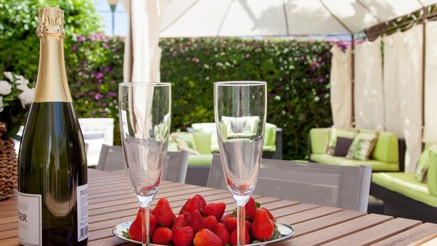 A table with a bottle of wine, two glasses, and a plate of strawberries.