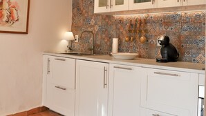 A kitchen with white cabinets, a tiled backsplash, and a coffee machine.