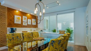 A modern dining area with a glass table and yellow patterned chairs, a brick accent wall, and a view of the outdoors. - A la luna de Valencia, 4-6 pax, 2 Bedrooms & 2 Bathrooms in downtown Valencia (Valencia)