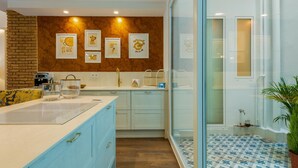A modern kitchen with a central island, light blue cabinets, a brick accent wall, and framed artwork on the wall. - A la luna de Valencia, 4-6 pax, 2 Bedrooms & 2 Bathrooms in downtown Valencia (Valencia)