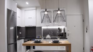 A modern kitchen with a central island, stainless steel appliances, and pendant lighting. - Alpinia Deluxe Apt Must (Thessaloniki)