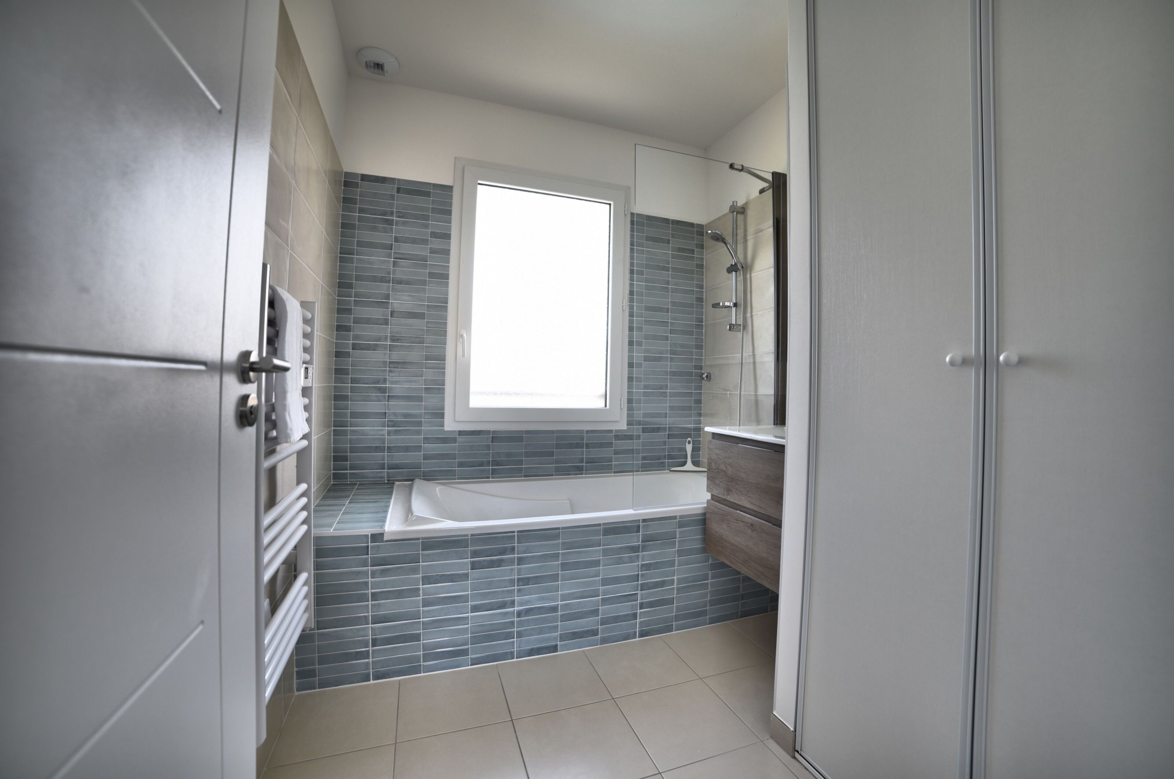 Een moderne badkamer met een badkuip, douche en een raam voor natuurlijk licht.