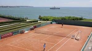 A tennis court with a net, surrounded by a green hedge and a sign for Casino Royale. - Villa 3 by Avecoeur (Saint-Augustin)