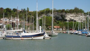 A marina with several boats docked, a rocky hillside in the background, and a clear sky. - Villa 3 by Avecoeur (Saint-Augustin)
