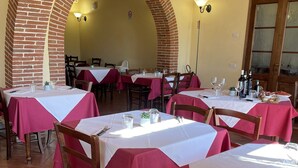 A restaurant with brick arches, tables with red tablecloths, and tiled flooring. - COLORINO APARTMENT on two floors BEDROOMS-KITCHEN-LIVING ROOM-AIR CONDITIONING   (Cerreto giudi)