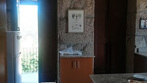 Een keuken met stenen muren, een houten kast, een aanrecht met borden en een lijst met een foto aan de muur.
