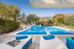 Un espace aménagé au bord de la piscine, avec des chaises longues et une piscine.