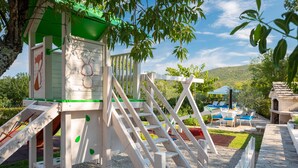 Ein Spielbereich für Kinder mit Rutsche, Kletterstufen und einer kleinen Haus-Konstruktion.