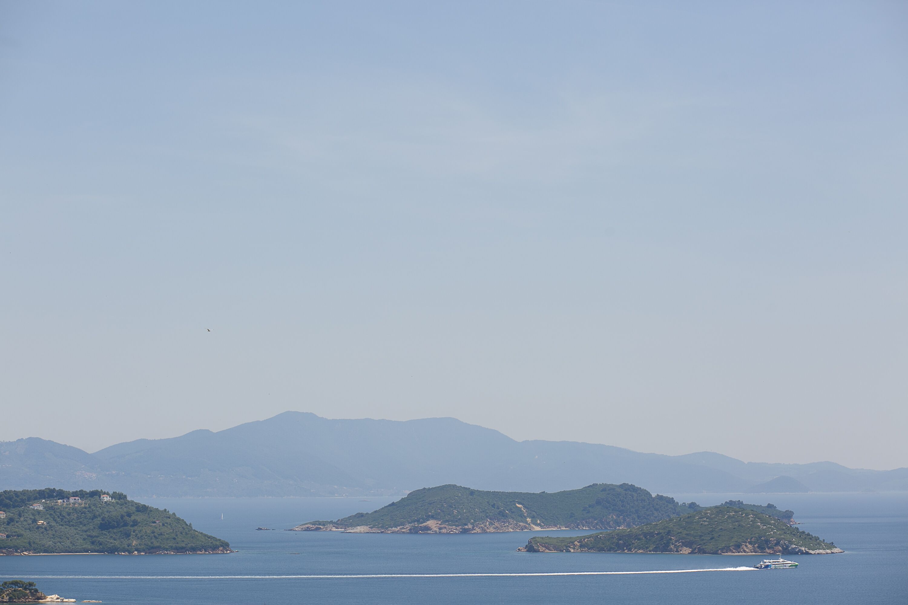 A coastal landscape with multiple islands and a boat in the water.