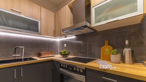 A modern kitchen with a stainless steel stove, oven, and dishwasher, wooden cabinets, and a marble backsplash. - IO.DELUXE 2ΒR, 2 BTHR.VILLA WITH PRIVATE POOL  AND STUNNING SEA VIEWS  (SKIATHOS)