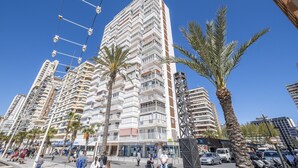 A high-rise building with multiple balconies, palm trees, and a clear blue sky. - Veracruz 18-A (Benidorm)