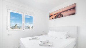 A hotel room with a large bed, a window with a city view, and a painting on the wall. - Veracruz 18-A (Benidorm)