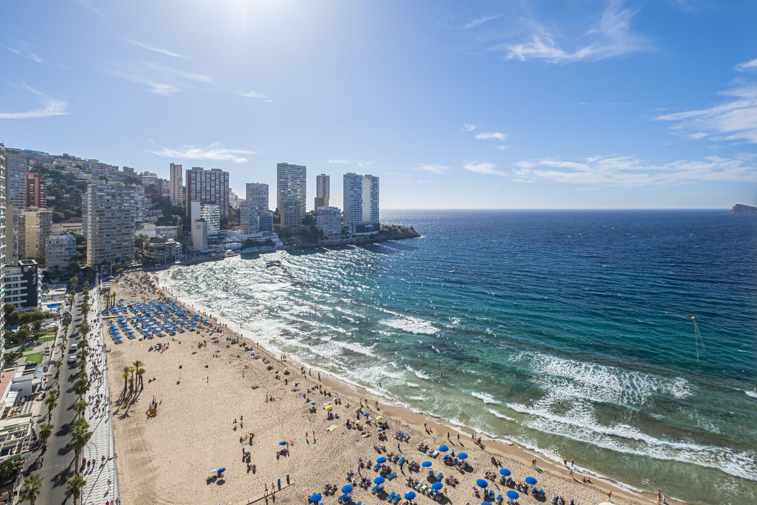 Un paysage urbain côtier avec une plage, des immeubles de grande hauteur et un ciel dégagé.