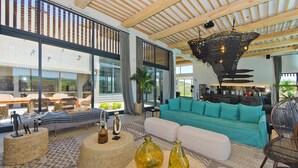 A spacious living area with a large sofa, wicker furniture, and a unique ceiling light fixture. - The One @ Pezula  (Knysna)