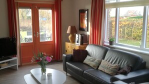 Un salon avec un canapé, une table basse, un téléviseur et une fenêtre avec des rideaux.