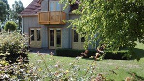 Une maison à deux étages dotée d’un balcon, d’une façade en briques et d’une pelouse bien entretenue.