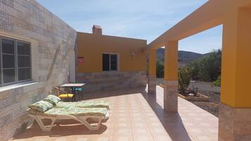 Relax on the patio with a comfortable lounge chair and a small table, surrounded by a hilly landscape.